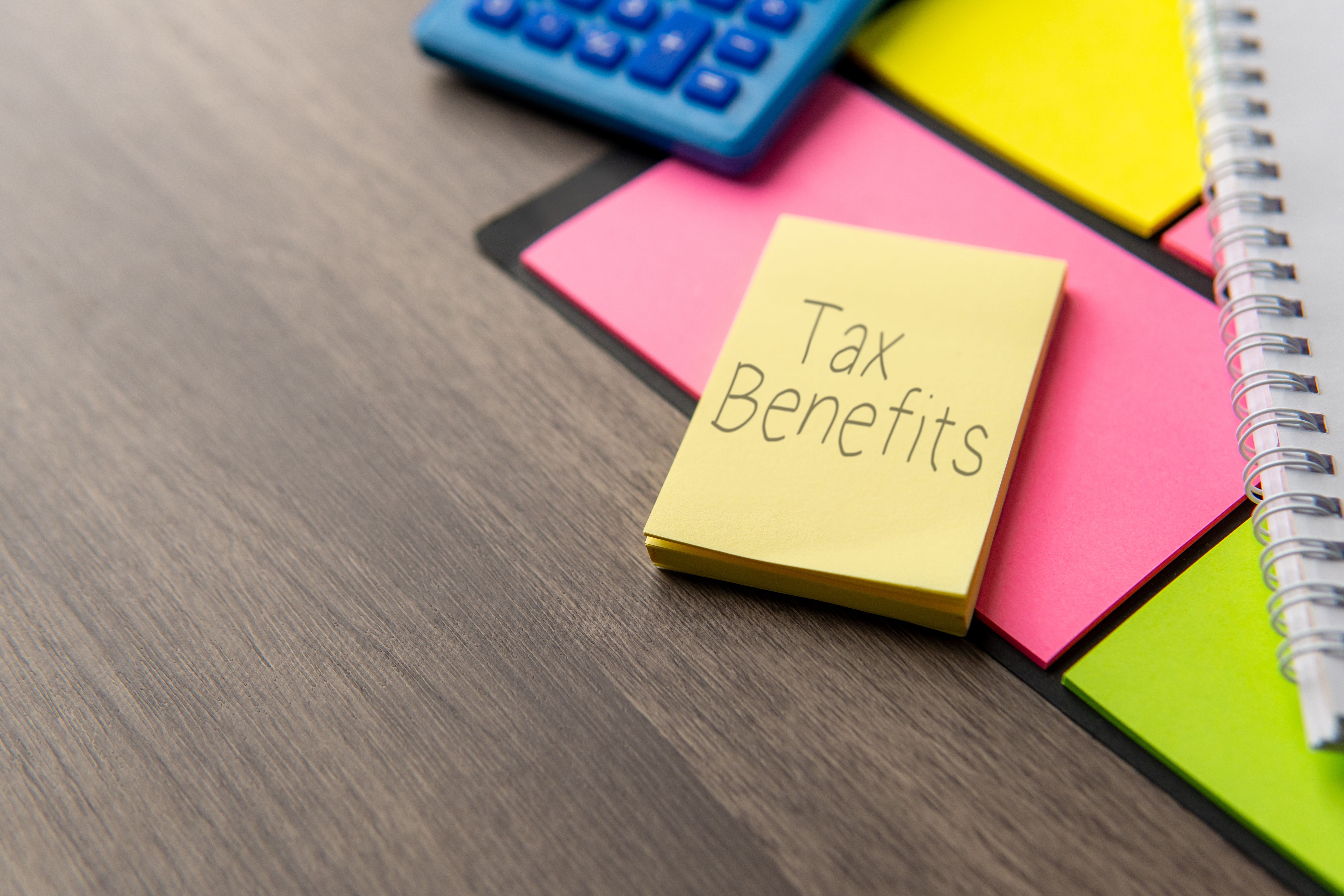 This is a photograph showing a close-up of a wooden desk surface with various brightly colored sticky notes and office supplies.