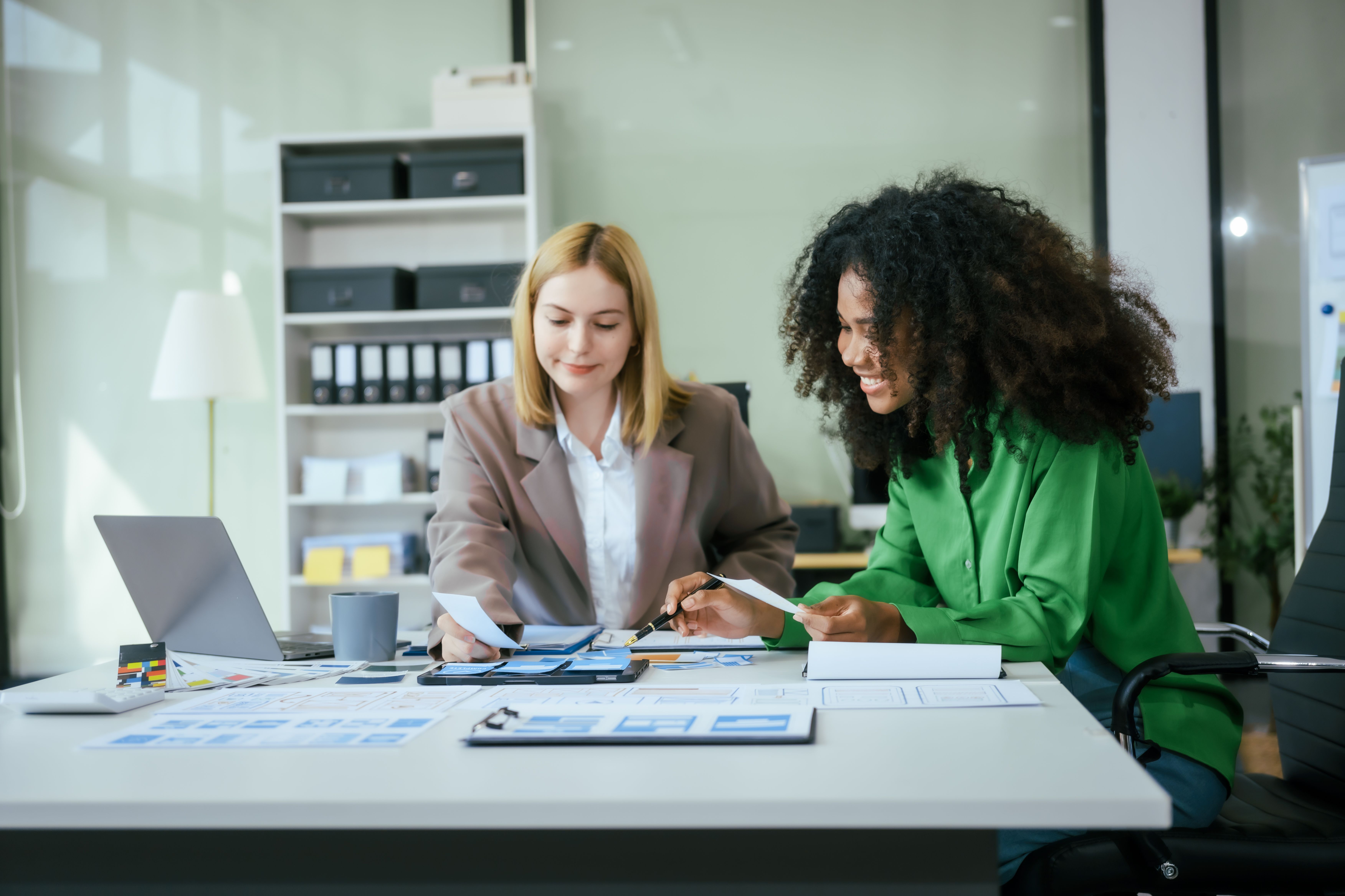 A photograph shows two women in a modern office. 