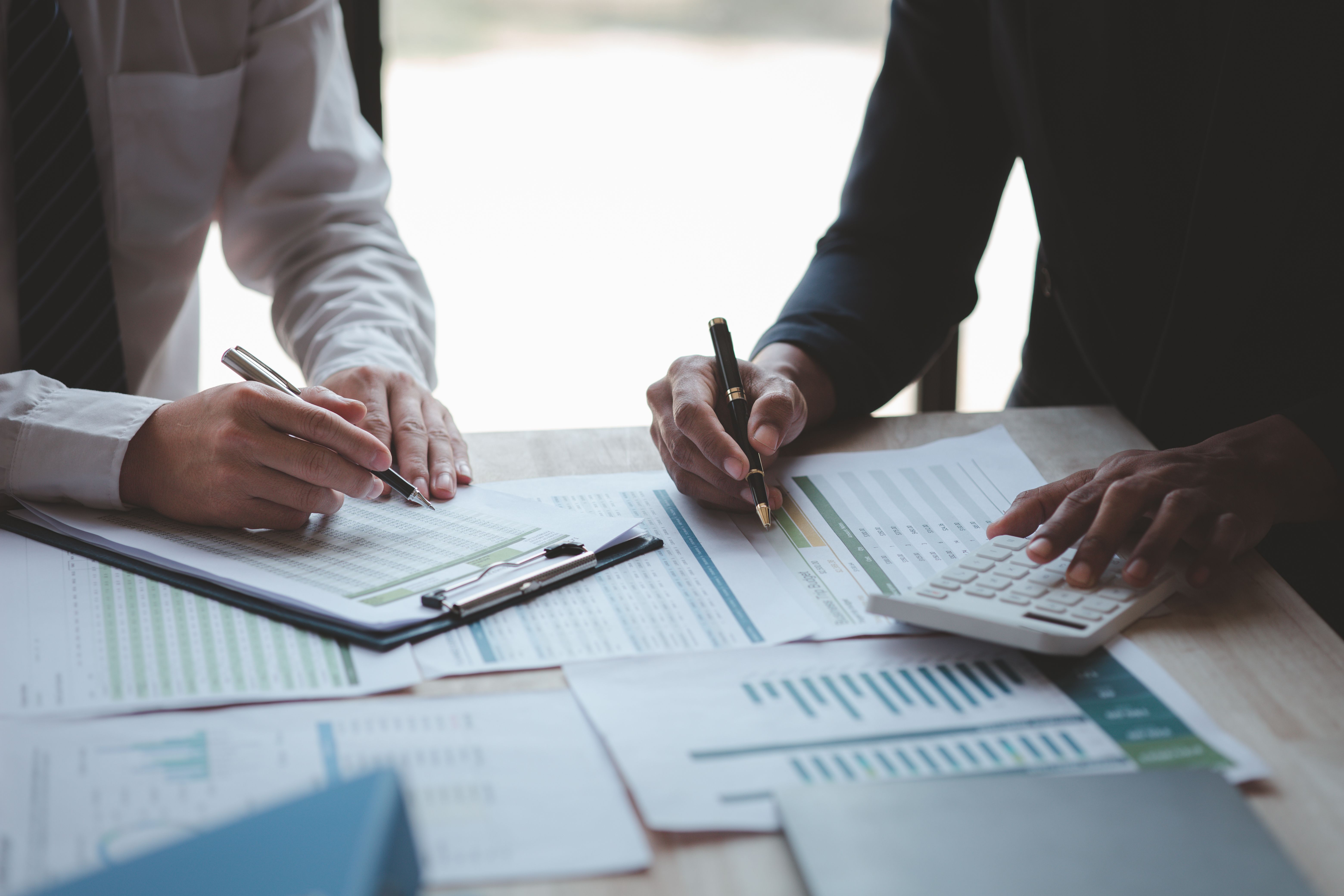 This photograph depicts two business professionals, a man and a woman, seated across a wooden desk.