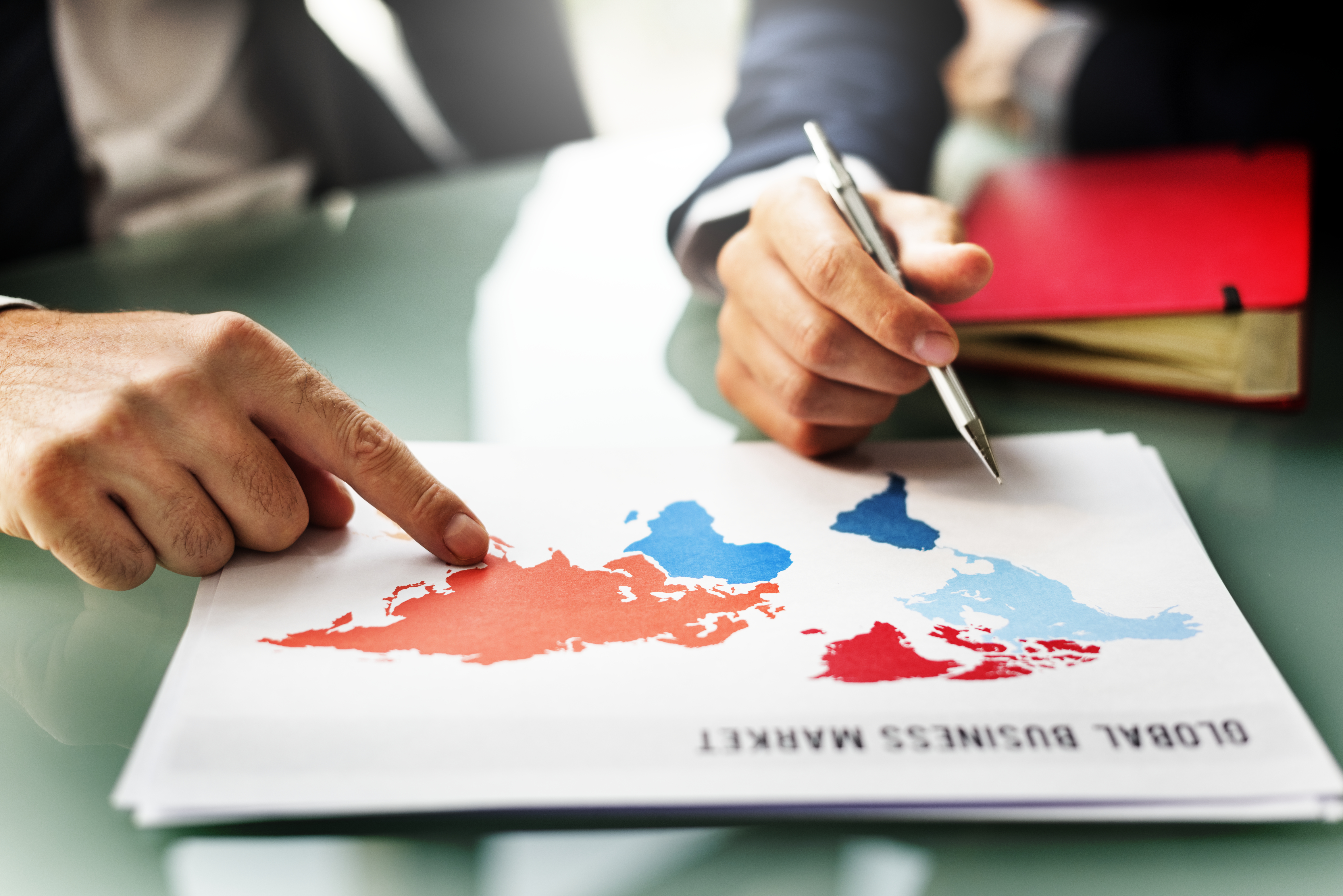 A photograph of a smiling, young woman with medium-length dark hair, wearing a black blazer. She is holding a white calculator and looking at a laptop screen in front of her.
