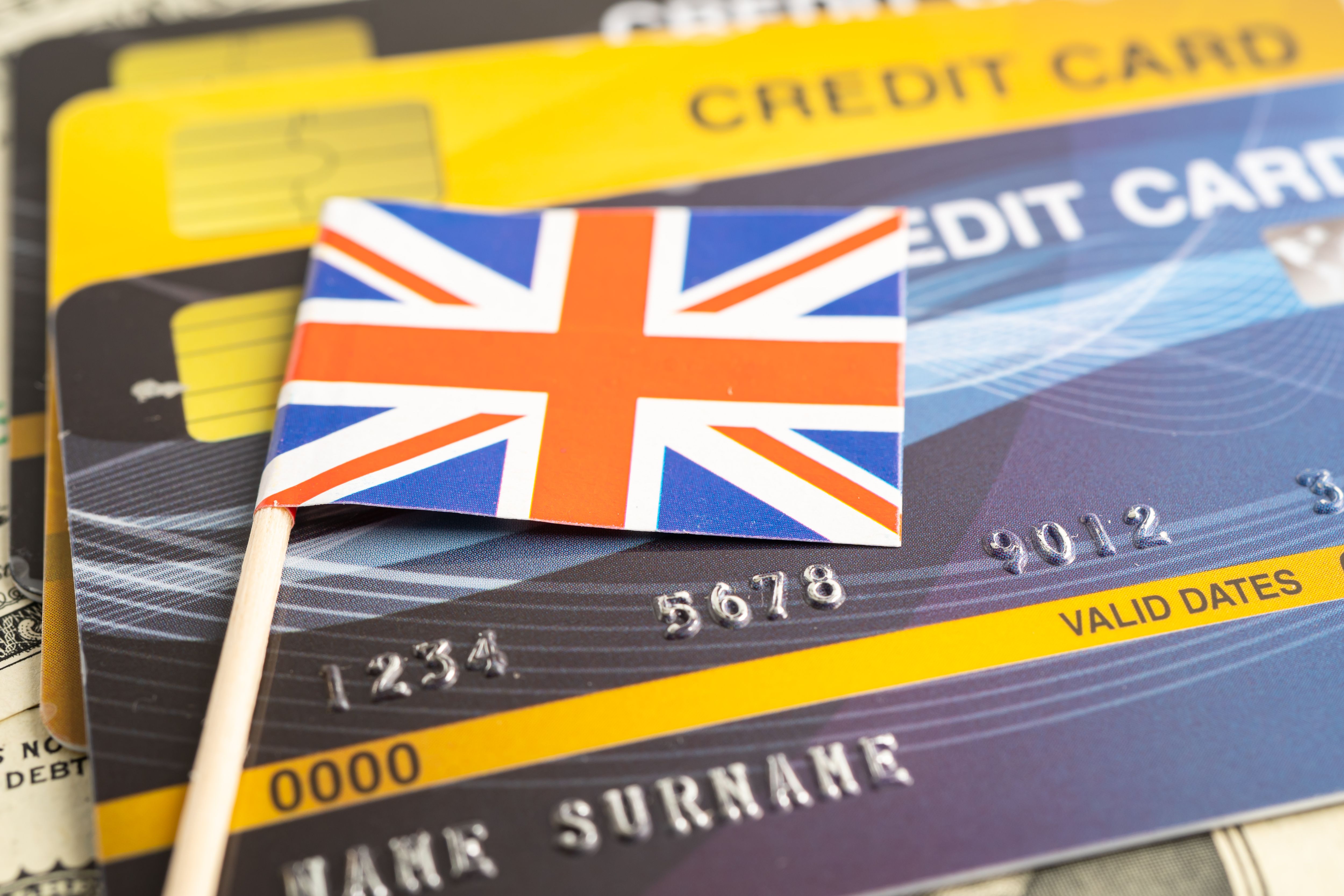 This is a photograph featuring a British Union Jack flag pin on a credit card. 