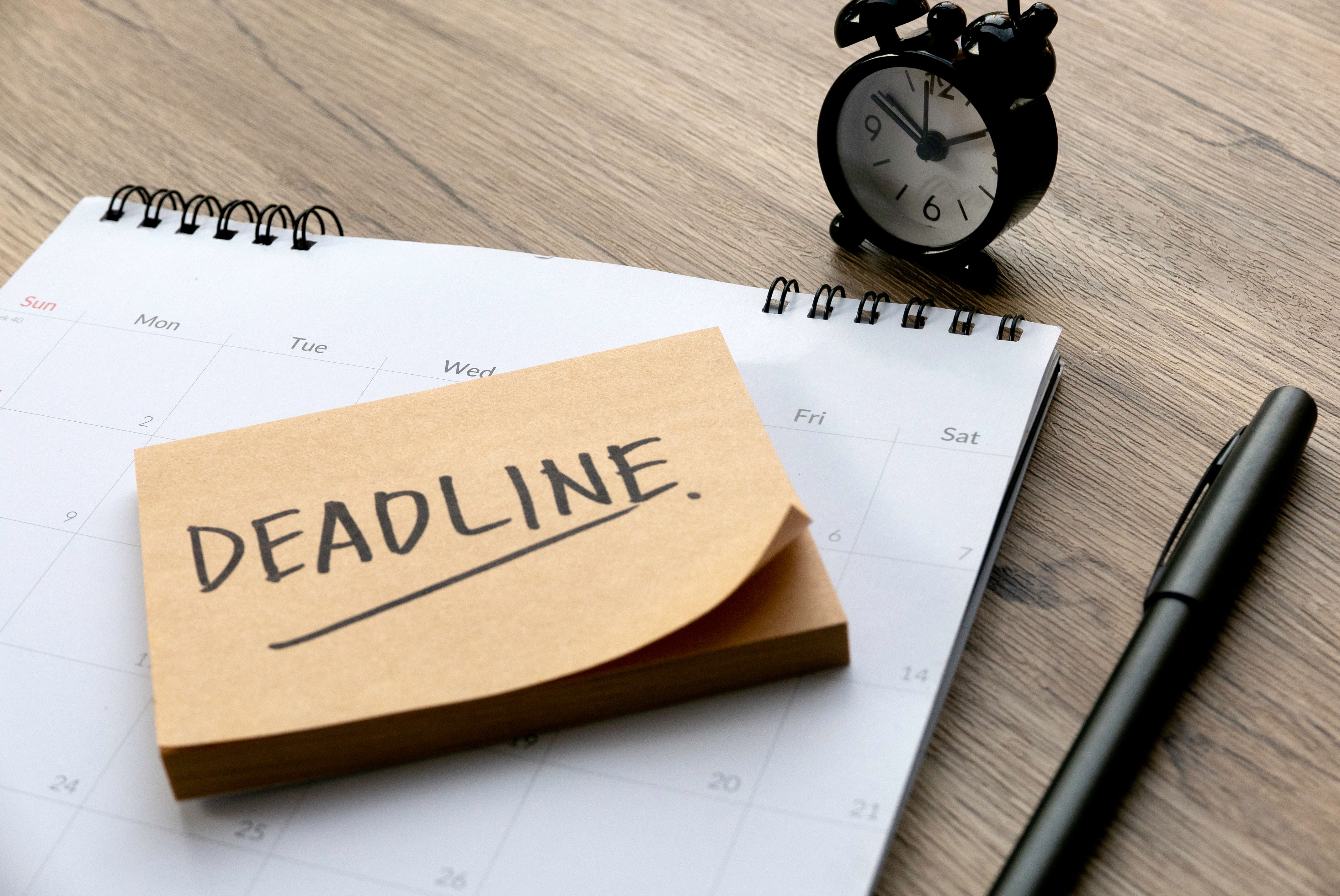 The notebook has a calendar page visible, with the word "DEADLINE" written in bold black marker on a sticky note on top.