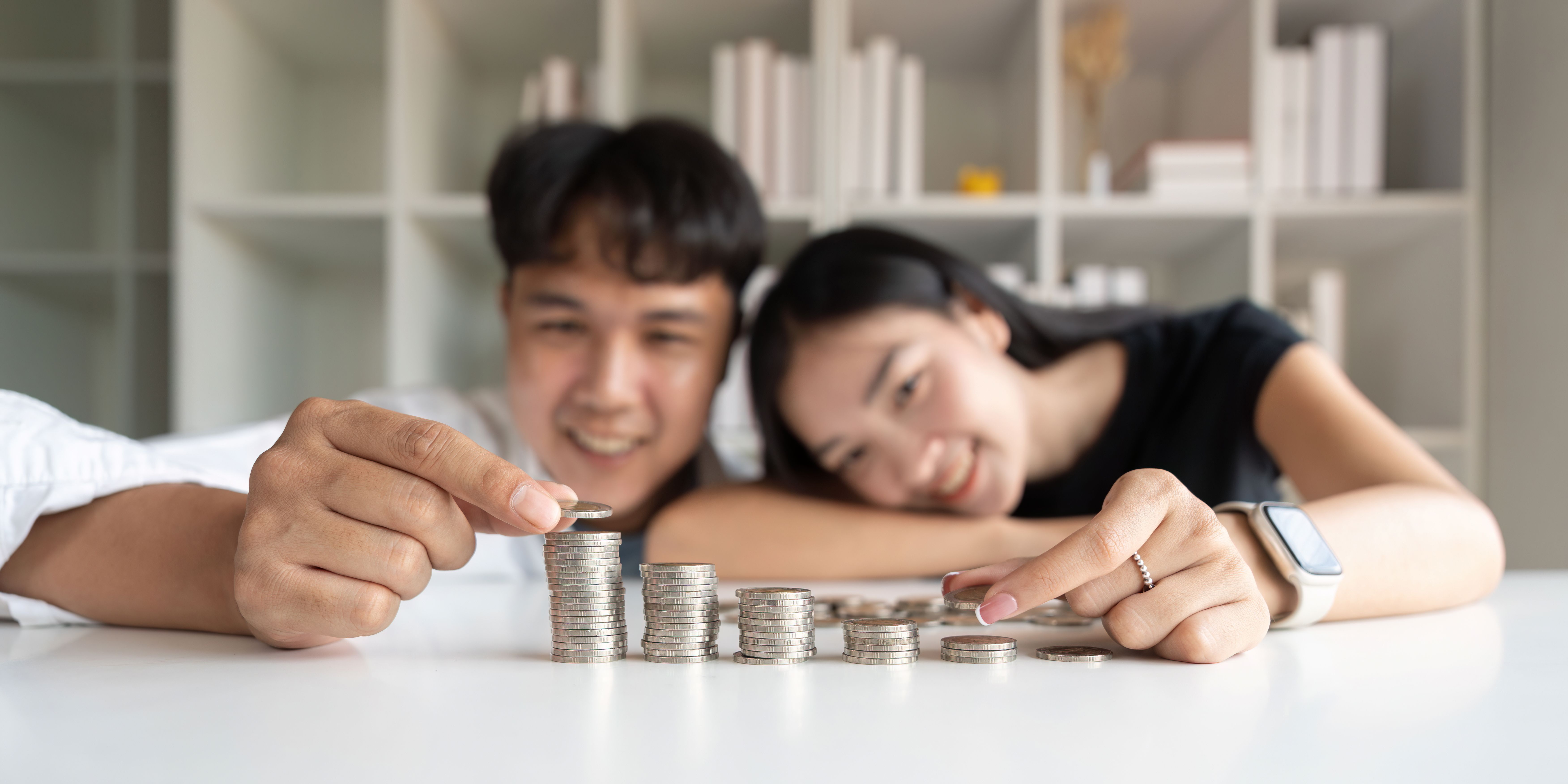 Asian couple lying on a white table counting coins